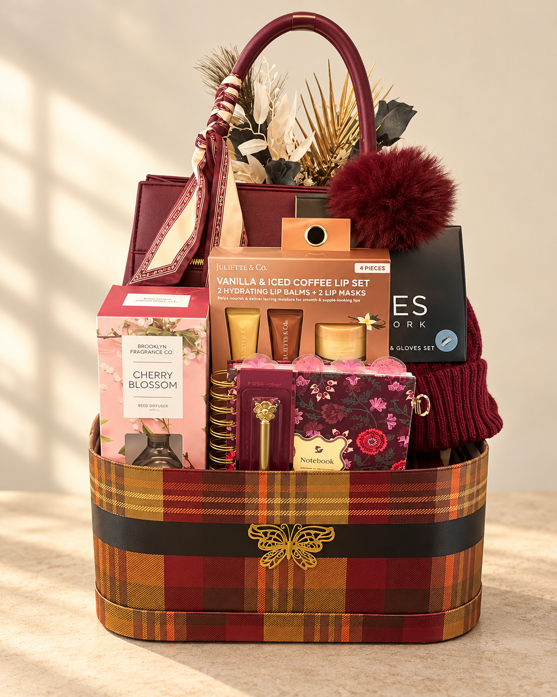 Handmade autumn plaid gift basket with a burgundy handbag, scarf, knit accessories, cherry blossom diffuser, and floral notebook